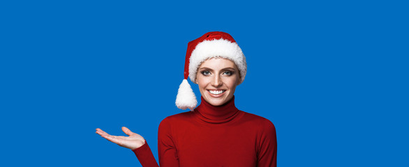 Adorable lady in santa hat holding something on a blue background