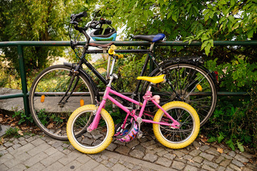 Fototapeta na wymiar 2 Fahrräder, ein Kinderrad und ein Erwachsenenrad, beide sind zusammen an ein Geländer gekettet
