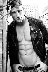 Handsome blonde man with open leather jacket revealing sixpack abs and looking at camera