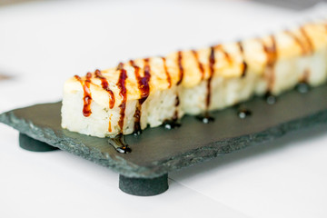 Freshly cooked uncut sushi roll on black board