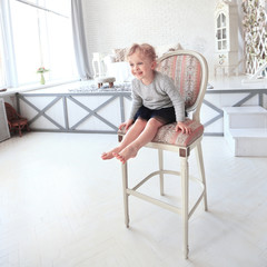 portrait of happy little girl sitting on a chair in the spacious