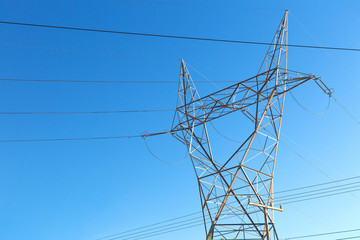 power line and electricity concept - transmission tower over blue sky