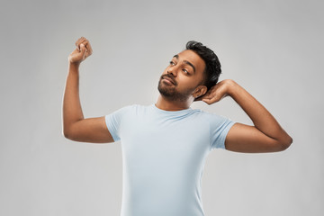 rest, bedtime and people concept - indian man stretching over grey background