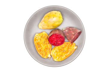 Group of one whole four halves of fresh bright prickly pear opuntia on grey ceramic plate flatlay isolated on white background