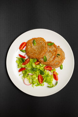 Potato pancakes with fresh mix of salad on a plate close-up.
