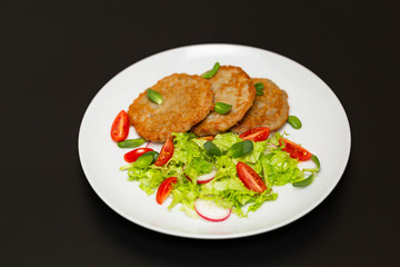 Potato pancakes with fresh mix of salad on a plate close-up.