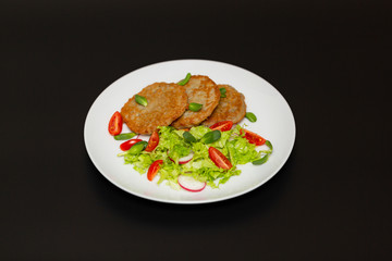 Potato pancakes with fresh mix of salad on a plate close-up.