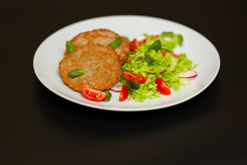Potato pancakes with fresh mix of salad on a plate close-up.