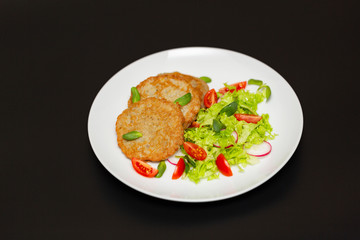 Potato pancakes with fresh mix of salad on a plate close-up.