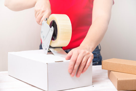 Woman packing cardboard boxes using tape dispenser