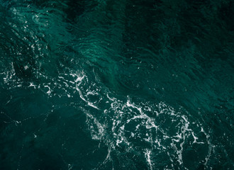 Blue-green sea background with white foam - texture of deep sea water, top view.