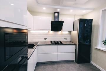  interior of a modern compact white kitchen with gas stove, oven, refrigerator. built-in furniture household appliances.