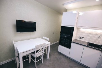  modern white kitchen interior, table, TV armchairs.
