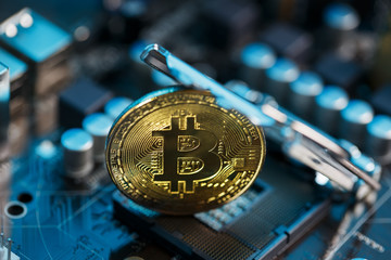 Golden Bitcoin Cryptocurrency on computer circuit board CPU. Macro shot.