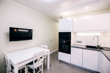  modern white kitchen interior, table, TV armchairs.