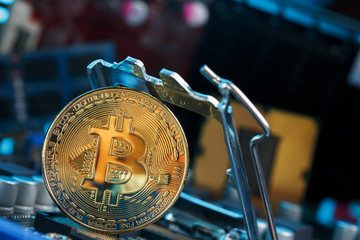 Golden Bitcoin Cryptocurrency on computer circuit board CPU. Macro shot.