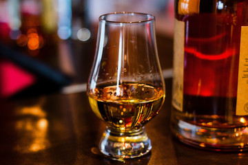 glass and bottle of whiskey close up with bokeh