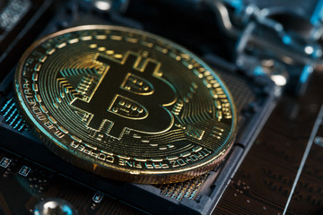 Golden Bitcoin Cryptocurrency on computer circuit board CPU. Macro shot.