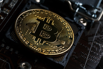Golden Bitcoin Cryptocurrency on computer circuit board CPU. Macro shot.