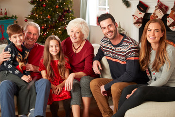 Portrait Of Multi Generation Family Sitting On Sofa In Lounge At Home On Christmas Day