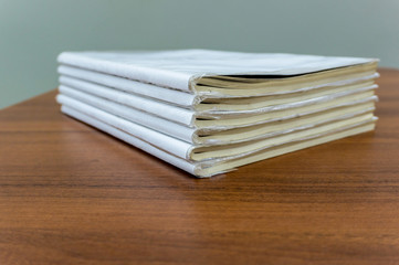 A stack of books are lying on a brown table, documents are stacked close-up.