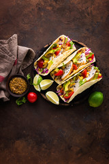 Fototapeta na wymiar Mexican tacos with chicken meat, vegetables and fresh greens
