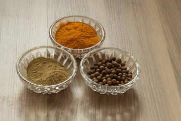 Ground and whole red and black pepper is poured into small transparent saucers