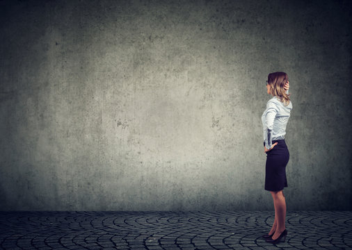 Business woman standing in front of a wall being challenged