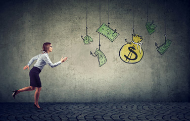 Business woman motivated by money hanging on a fishing hook.