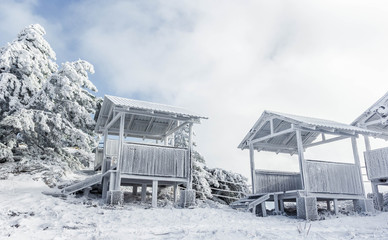 Wooden gazebo for relaxation. Gazebo in a snow-covered mountain forest. Trees covered with snow.