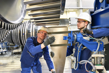 Teamwork - workers manufacturing steam turbines in an industrial factory