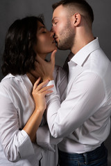 Closeup of a beautiful couple wearing white shirts. The girl and the man passionately almost touch their lips to each other. Casual style. Lifestyle, fashion, commercial design.