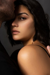 Closeup of a beautiful couple. A man sensually touches his lips to the forehead of a girl whose shoulder is bare. Casual fashionable style. Lifestyle, fashion, commercial design