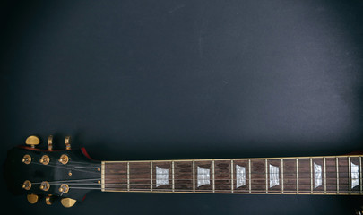 Top view of guitar neck, black background, copy space.