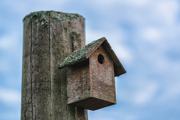 Picture of old wooden bird house with dramatic blue sky ath the background