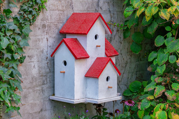 Picture of painted bird house on the wall with green leaves