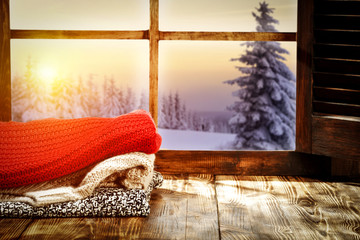 Fototapeta na wymiar Winter window and start wooden table with warm cloths 