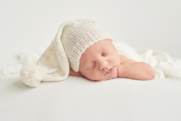 Cute newborn baby lies swaddled in a white blanket. Baby goods packaging template. Closeup portrait of newborn baby with smile on face. Healthy and medical concept. 