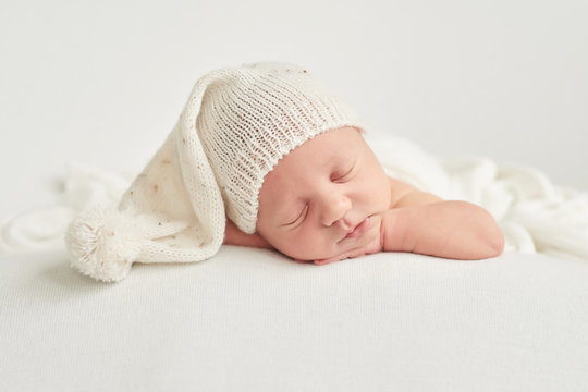 Cute newborn baby lies swaddled in a white blanket. Baby goods packaging template. Closeup portrait of newborn baby with smile on face. Healthy and medical concept. 