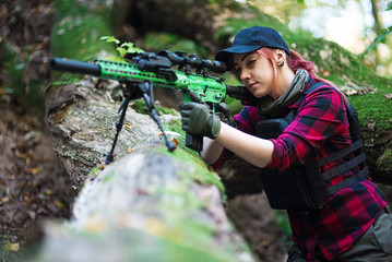 Woman hunter aims with a rifle/Young woman is aiming from a sniper rifle in the forest while...