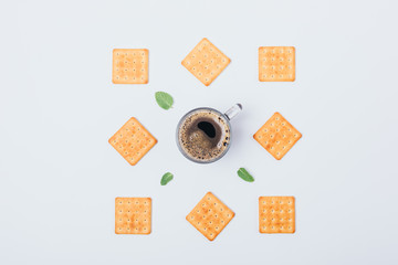Flat layout of cookies, green leaves and cup of black coffee