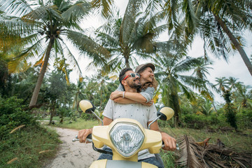 A loving couple travels by scooter through the jungle in Southeast Asia. Smiling and laughing happily © Anna