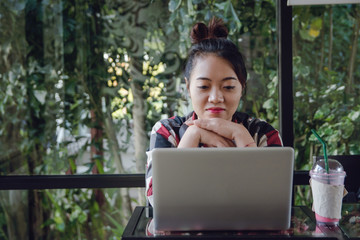 Young asia woman sitting alone and working on a laptop at coffee shop