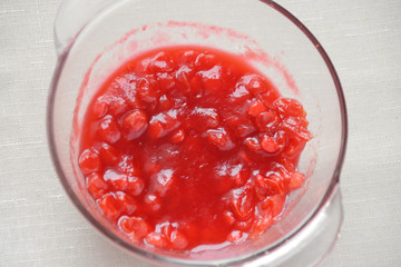 Sour red juicy organic vegetarian viburnum berries with sugar in glass bowl on blurred neutral table cloth. Food ingredient. Cooking source or jam