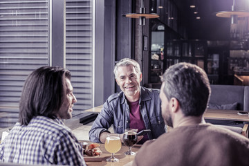 Joyful gray-haired young man communicating with his friends