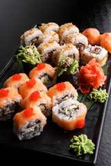 Philadelphia roll with salmon and cucumber. Maki Sushi set on dark pattern background. Sushi Set nigiri, rolls and sashimi served in black square plate. On dark pattern background.
