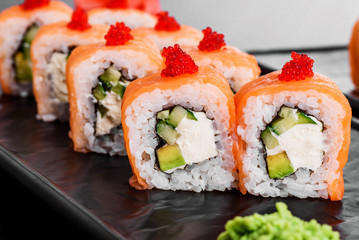 Philadelphia roll with salmon and cucumber. Maki Sushi set on dark pattern background. Sushi Set nigiri, rolls and sashimi served in black square plate. On dark pattern background.