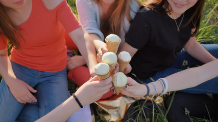 Five girls join hands clinking ice cream. Hands close-up.