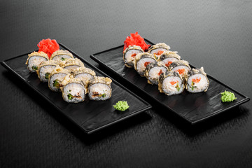 warm roll with salmon. Maki Sushi set on dark pattern background. Sushi Set nigiri, rolls and sashimi served in black square plate. On dark pattern background.