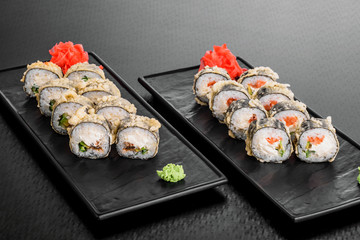warm roll with salmon. Maki Sushi set on dark pattern background. Sushi Set nigiri, rolls and sashimi served in black square plate. On dark pattern background.